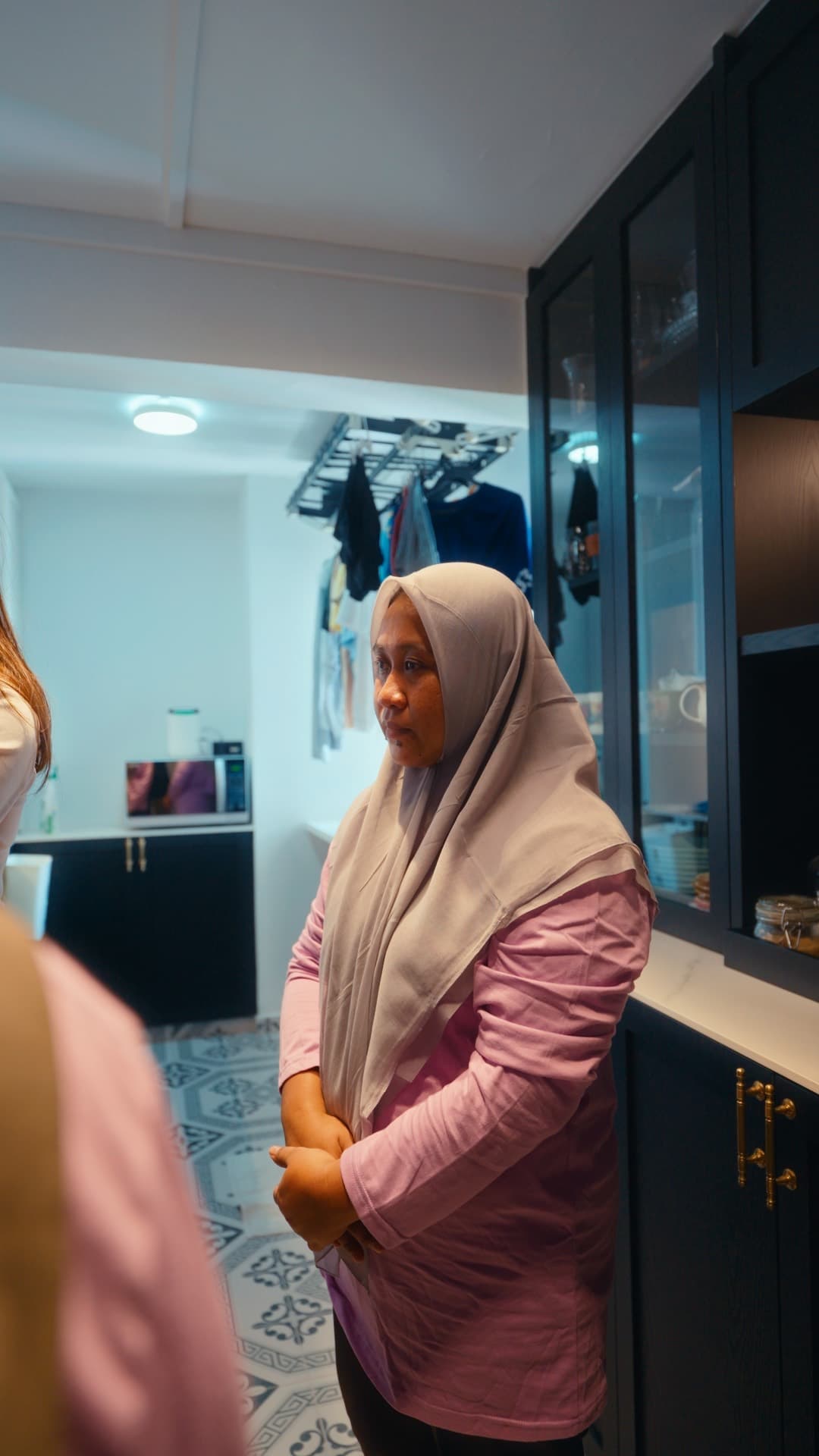 A helper being shown around the kitchen of a Singapore home by her employer during her first days in the household