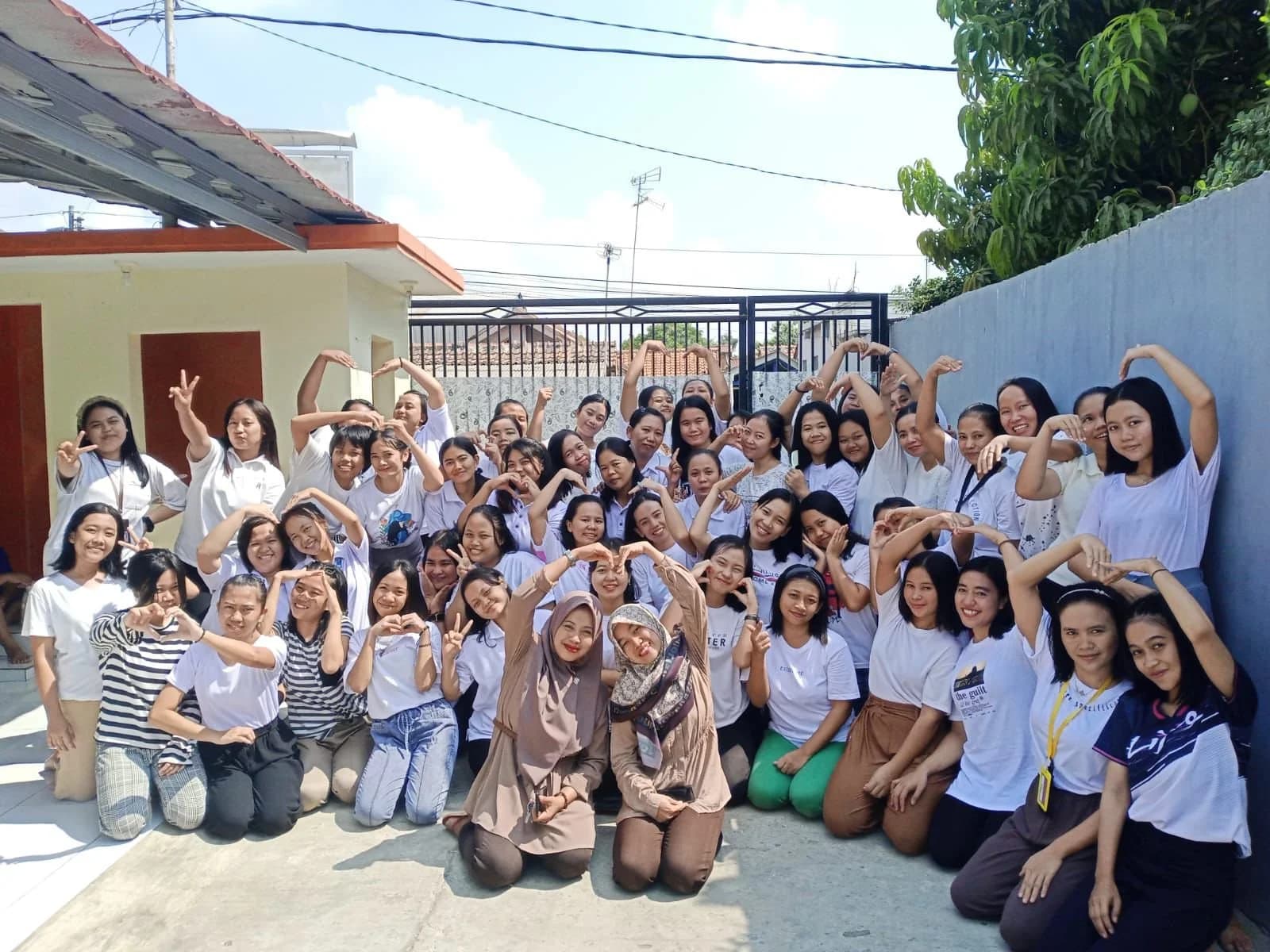A large group of trainee helpers photographed together in the courtyard of a training centre